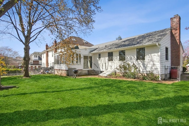 back of house featuring a chimney, entry steps, a gate, and a shingled roof
