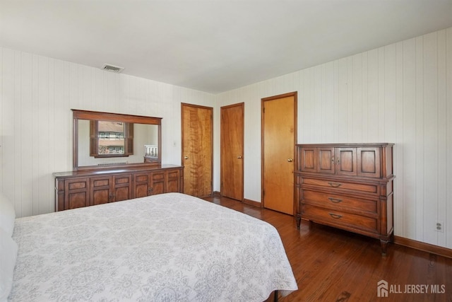 bedroom with dark wood finished floors, multiple closets, and baseboards
