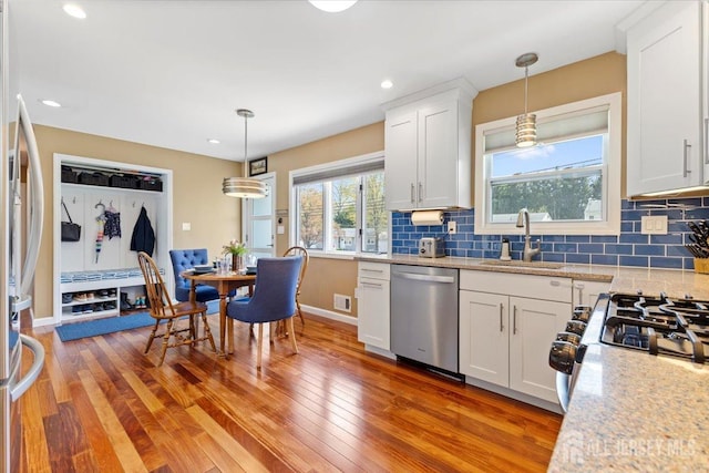 kitchen featuring stainless steel appliances, a sink, light wood-type flooring, decorative light fixtures, and recessed lighting