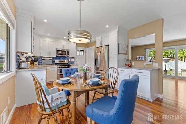 dining space with light wood-type flooring, recessed lighting, and baseboards