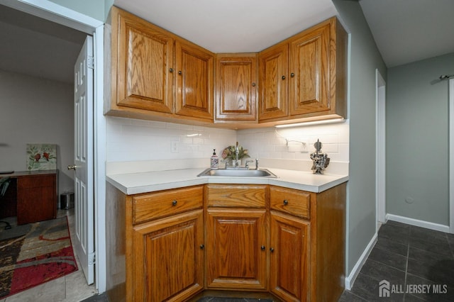 kitchen with light countertops, tasteful backsplash, brown cabinetry, and a sink