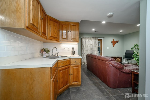 kitchen featuring a sink, open floor plan, light countertops, brown cabinets, and tasteful backsplash