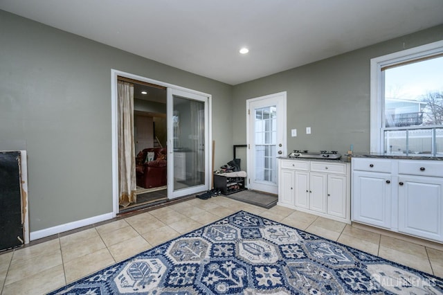 interior space featuring light tile patterned floors, stone countertops, baseboards, white cabinets, and recessed lighting