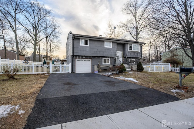 raised ranch with a garage, aphalt driveway, and fence