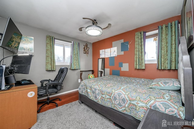 bedroom with ceiling fan, baseboards, and wood finished floors