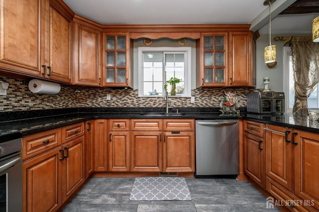 kitchen with backsplash, brown cabinets, oven, stainless steel dishwasher, and a sink