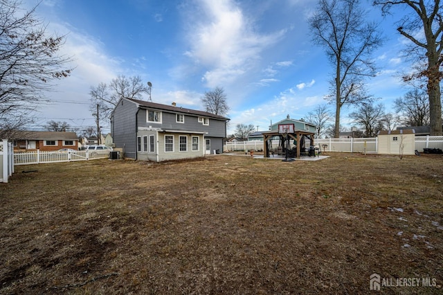 rear view of property with a gazebo, a lawn, an outdoor structure, and a fenced backyard