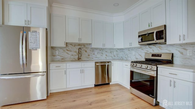 kitchen with decorative backsplash, sink, white cabinets, and appliances with stainless steel finishes