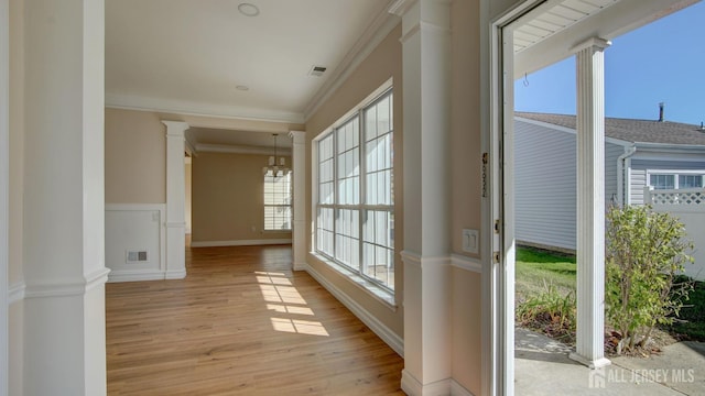 entryway featuring ornate columns, crown molding, an inviting chandelier, and light wood-type flooring