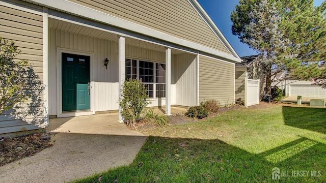 view of exterior entry with a lawn and covered porch