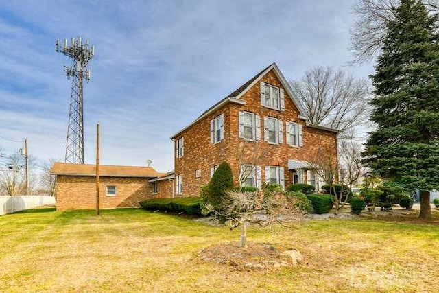 rear view of house with a yard, brick siding, and fence