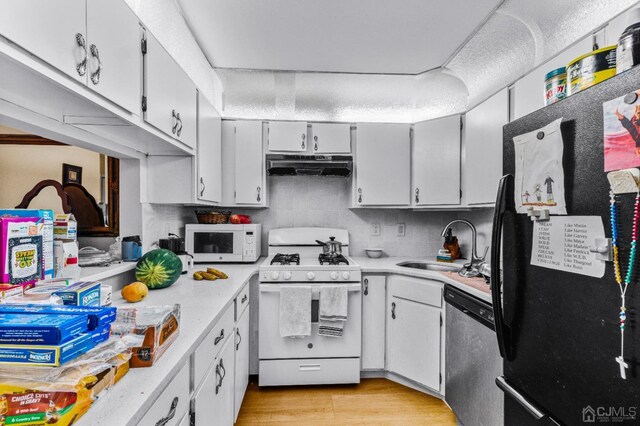 kitchen with white appliances, light wood finished floors, light countertops, under cabinet range hood, and white cabinetry