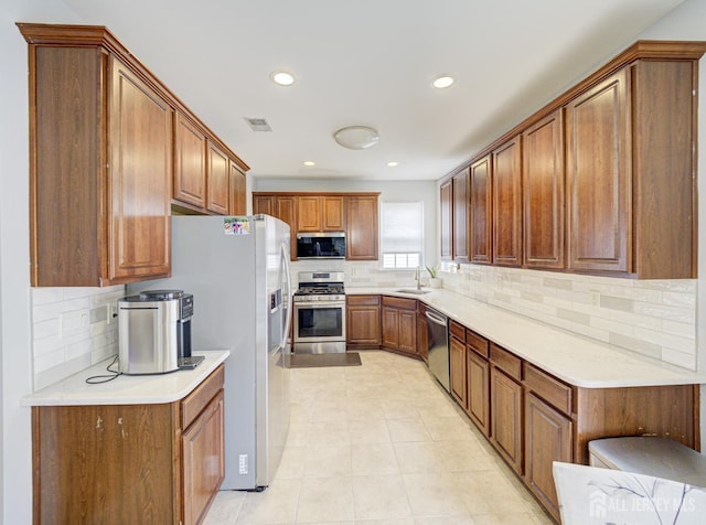 221 Morning Glory Dr, Monroe, NJ 08831 - kitchen featuring appliances with stainless steel finishes, a sink, decorative backsplash, brown cabinetry, and recessed lighting