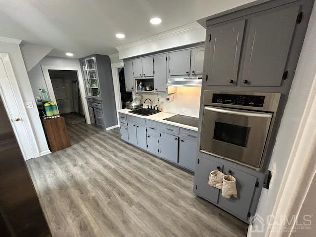 kitchen featuring light hardwood / wood-style floors, gray cabinets, sink, and oven