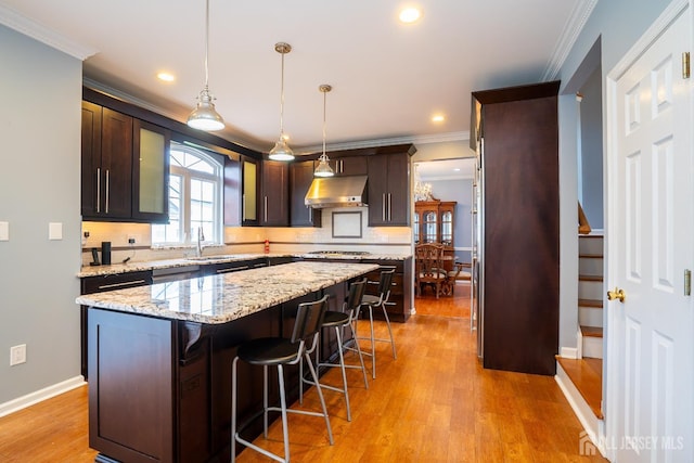 4 Bernadette Cir S, Brunswick, NJ 08852 - kitchen featuring under cabinet range hood, ornamental molding, tasteful backsplash, gas cooktop, and a kitchen island