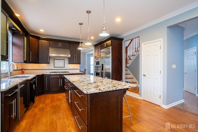 4 Bernadette Cir S, Brunswick, NJ 08852 - kitchen featuring a sink, under cabinet range hood, appliances with stainless steel finishes, crown molding, and a breakfast bar