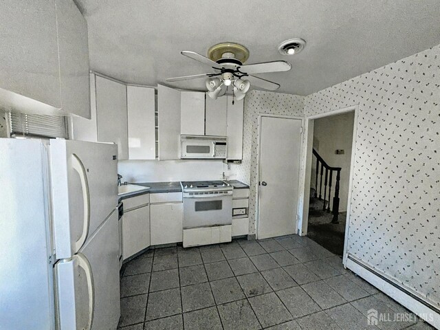 kitchen featuring white cabinetry, sink, ceiling fan, baseboard heating, and white appliances