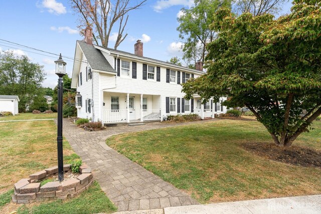 colonial-style house featuring a porch and a front yard