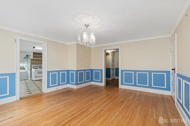 unfurnished room featuring hardwood / wood-style floors, a notable chandelier, and crown molding