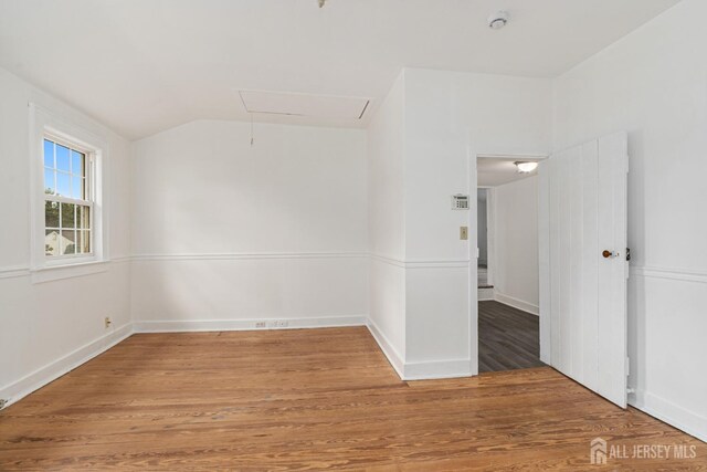 unfurnished room featuring hardwood / wood-style floors and vaulted ceiling