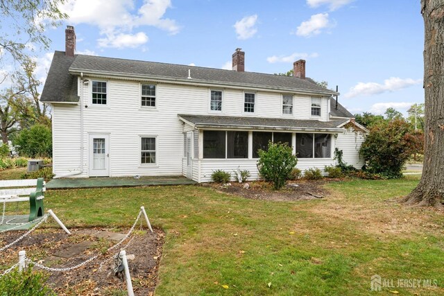 back of property with a patio area, a sunroom, and a yard