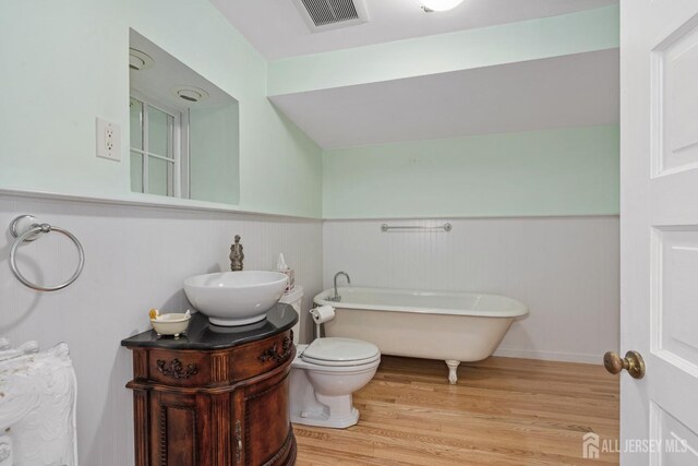 bathroom with a bathing tub, vanity, toilet, and hardwood / wood-style floors