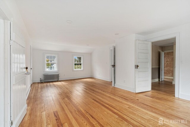 empty room with light wood-type flooring and radiator