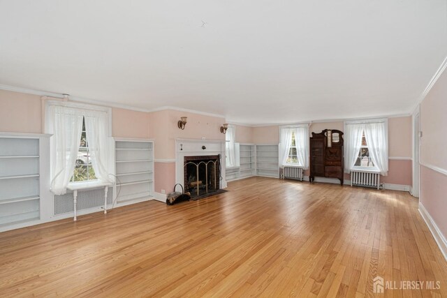 unfurnished living room featuring light wood-type flooring, radiator heating unit, and ornamental molding