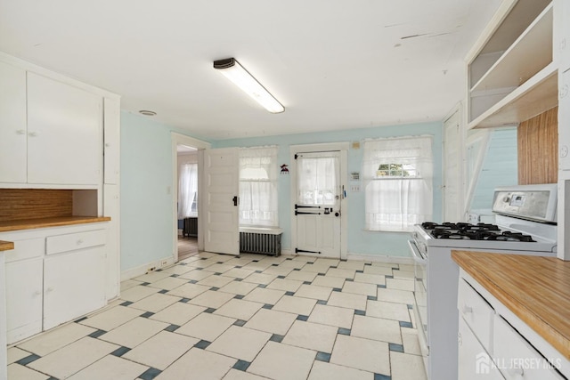 kitchen featuring white gas range, white cabinetry, and radiator