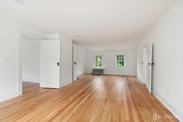 unfurnished living room with radiator and light wood-type flooring