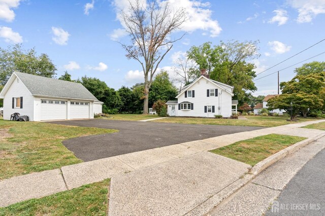 view of front of property with a garage, an outbuilding, and a front lawn