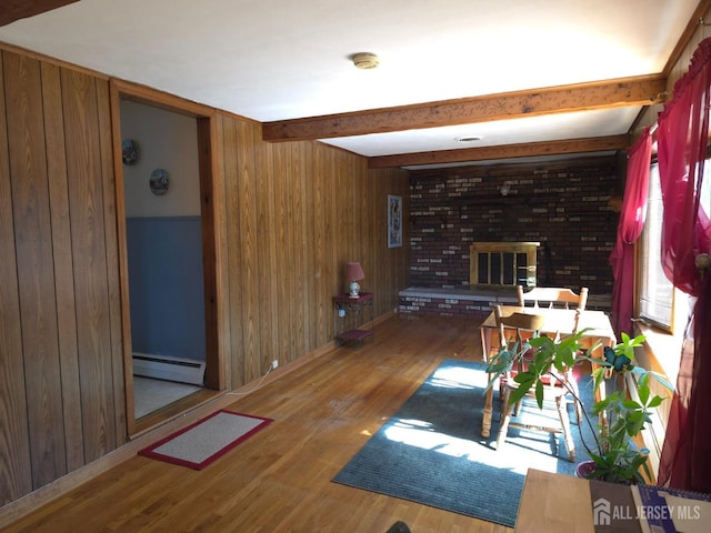 144 Buckelew Ave, Jamesburg, NJ 08831 - living area with wooden walls, a baseboard heating unit, wood finished floors, beam ceiling, and a brick fireplace