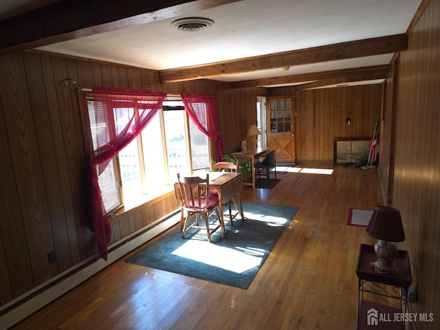 144 Buckelew Ave, Jamesburg, NJ 08831 - dining area featuring beamed ceiling, baseboard heating, wood walls, and wood finished floors