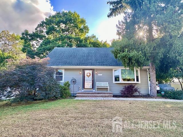 single story home featuring a front lawn and roof with shingles