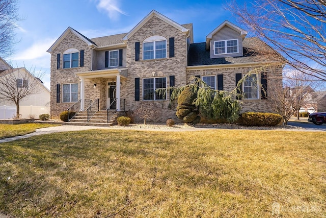 traditional-style house featuring a front yard and brick siding