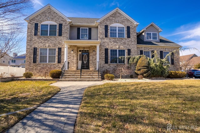 view of front facade featuring a front lawn, fence, and brick siding