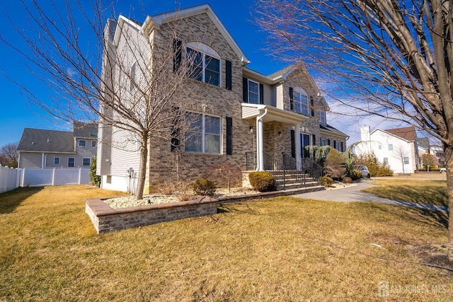 traditional home featuring brick siding, fence, and a front lawn