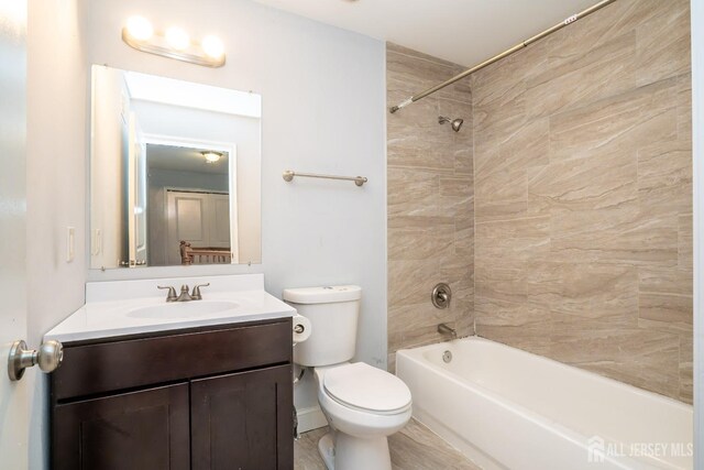 full bathroom with tiled shower / bath combo, vanity, and toilet