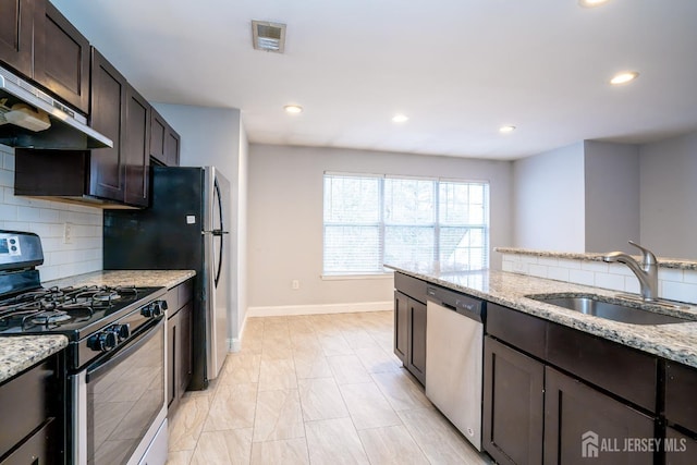 kitchen with sink, dark brown cabinets, light stone countertops, and stainless steel appliances