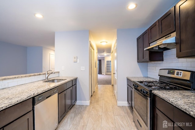 kitchen with appliances with stainless steel finishes, tasteful backsplash, sink, light stone counters, and dark brown cabinets