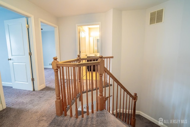 staircase featuring baseboards, visible vents, and carpet flooring