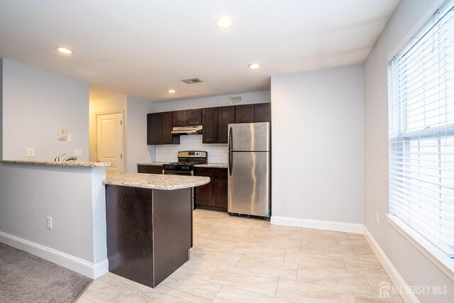 kitchen with dark brown cabinetry, plenty of natural light, appliances with stainless steel finishes, and tasteful backsplash