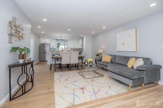 living room with an inviting chandelier and light hardwood / wood-style floors