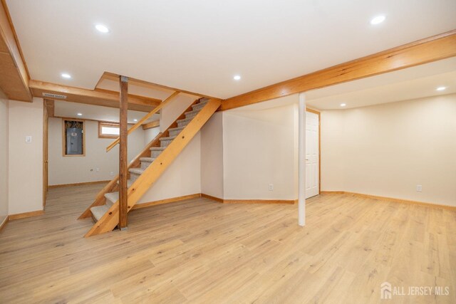 basement featuring electric panel and light wood-type flooring