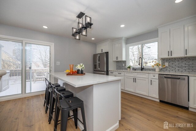 kitchen featuring appliances with stainless steel finishes, a center island, white cabinets, and decorative backsplash