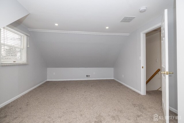 bonus room with vaulted ceiling and light colored carpet