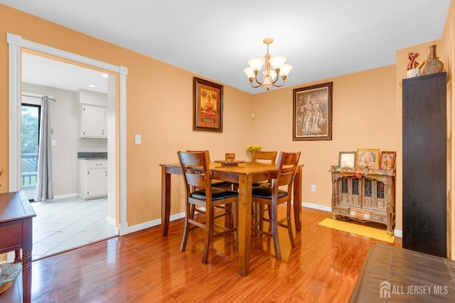 dining room with baseboards, a chandelier, and light wood-type flooring