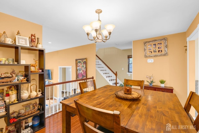 dining room with an inviting chandelier, stairway, and wood finished floors
