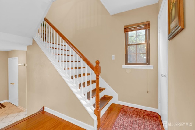staircase featuring wood finished floors and baseboards