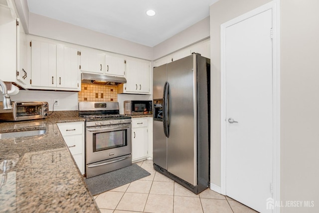 kitchen with a sink, stainless steel appliances, under cabinet range hood, light tile patterned floors, and white cabinetry